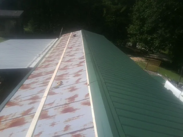 Old rusted panels beside newly installed green metal roofing — Wind Damage Roof Repair by Roofing Brothers in Rahway