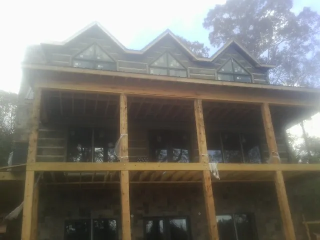 Dormers and porch framing on a large log home under construction — Roof Coating work by our crew in Rahway
