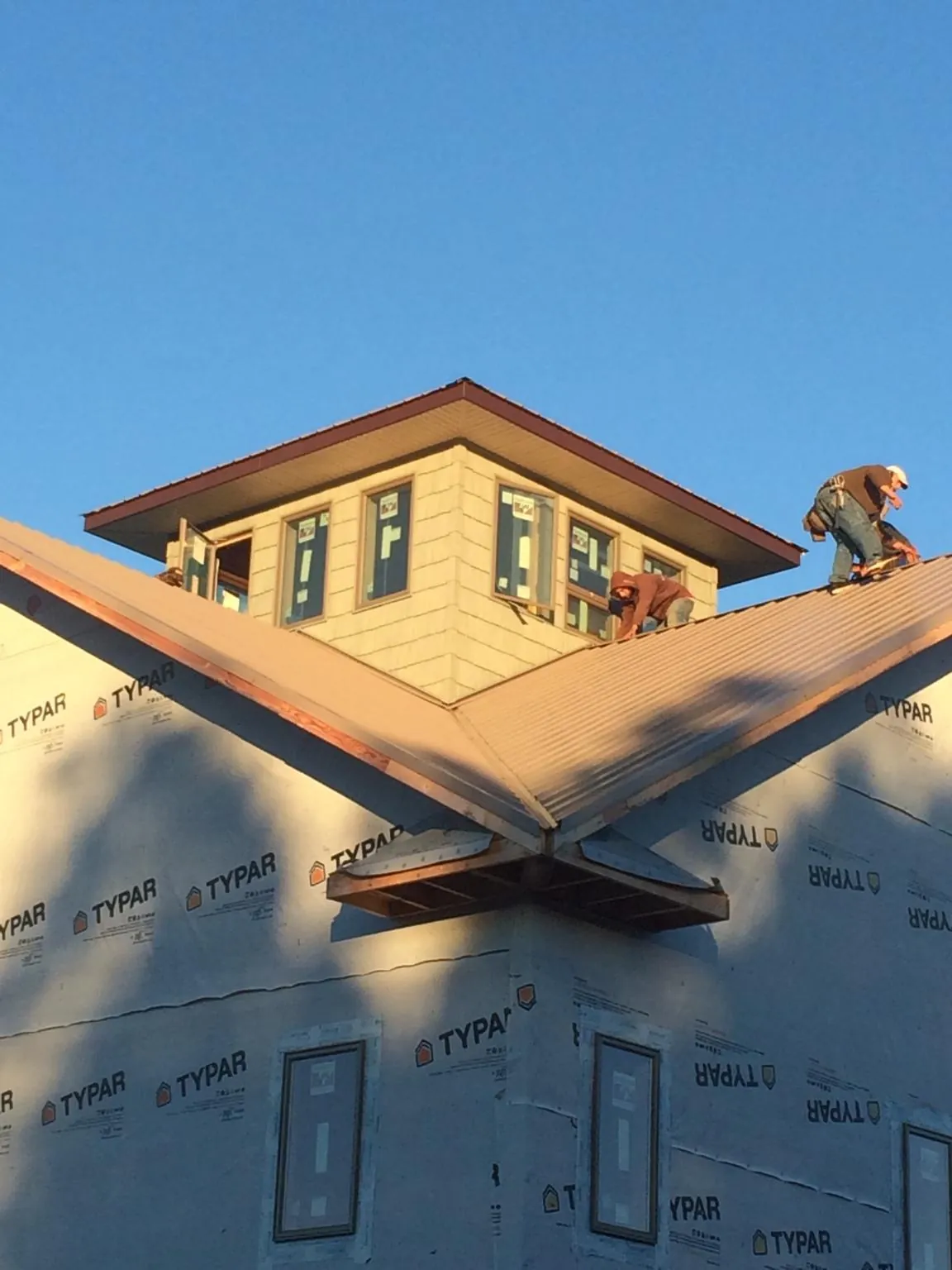 Roofers working around a rooftop cupola on a new metal roof at sunset — Roof Waterproofing in Rahway by Roofing Brothers
